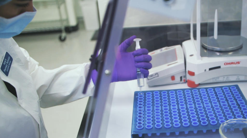 Lab Technician Filling Small Vials with a Syringe